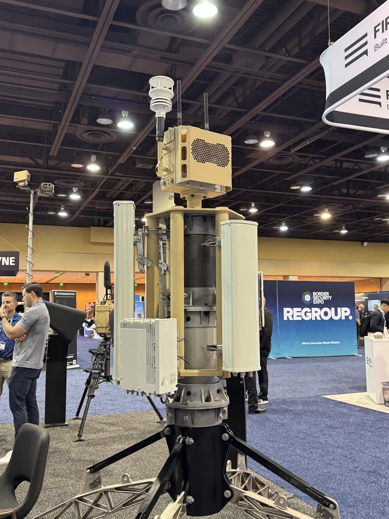 Tall tan deployable electronics and sensor mast at an industry exhibition