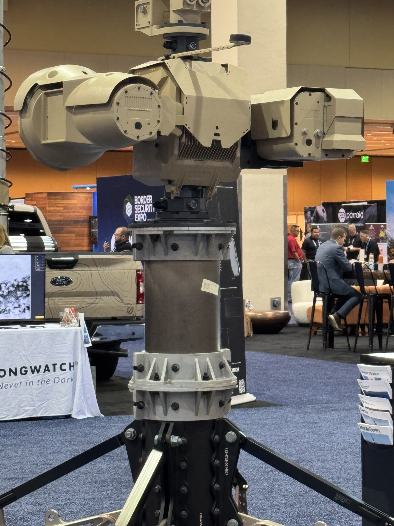 Tan multi-sensor turret mounted on a mast at an industry exhibition