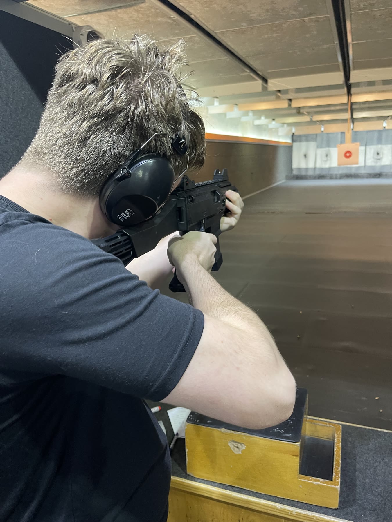 Person wearing hearing protection firing a carbine at an indoor range